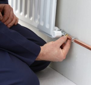 Man adjusting a thermal dial on a radiator